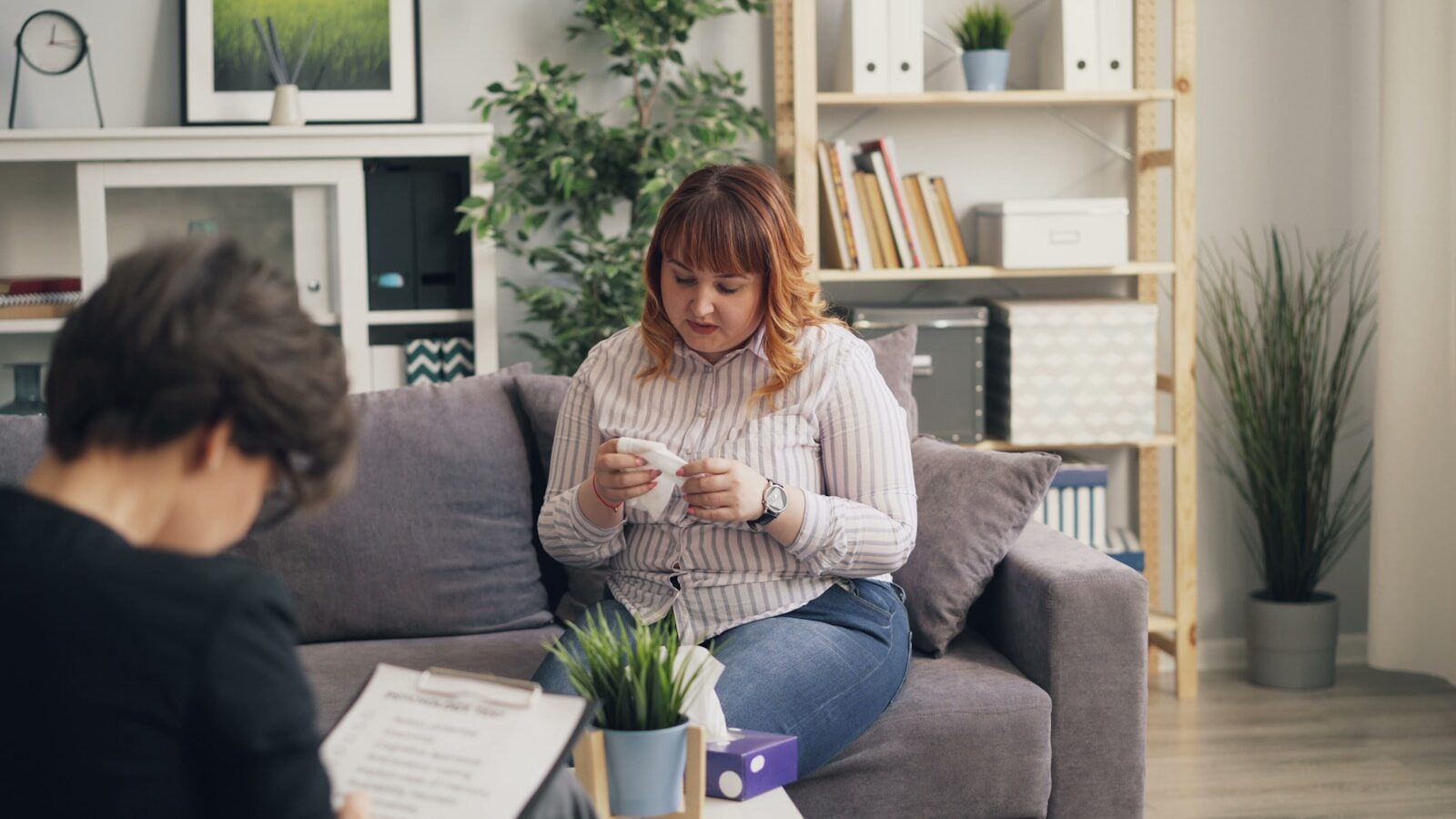 a woman sitting on a couch looking at a cell phone